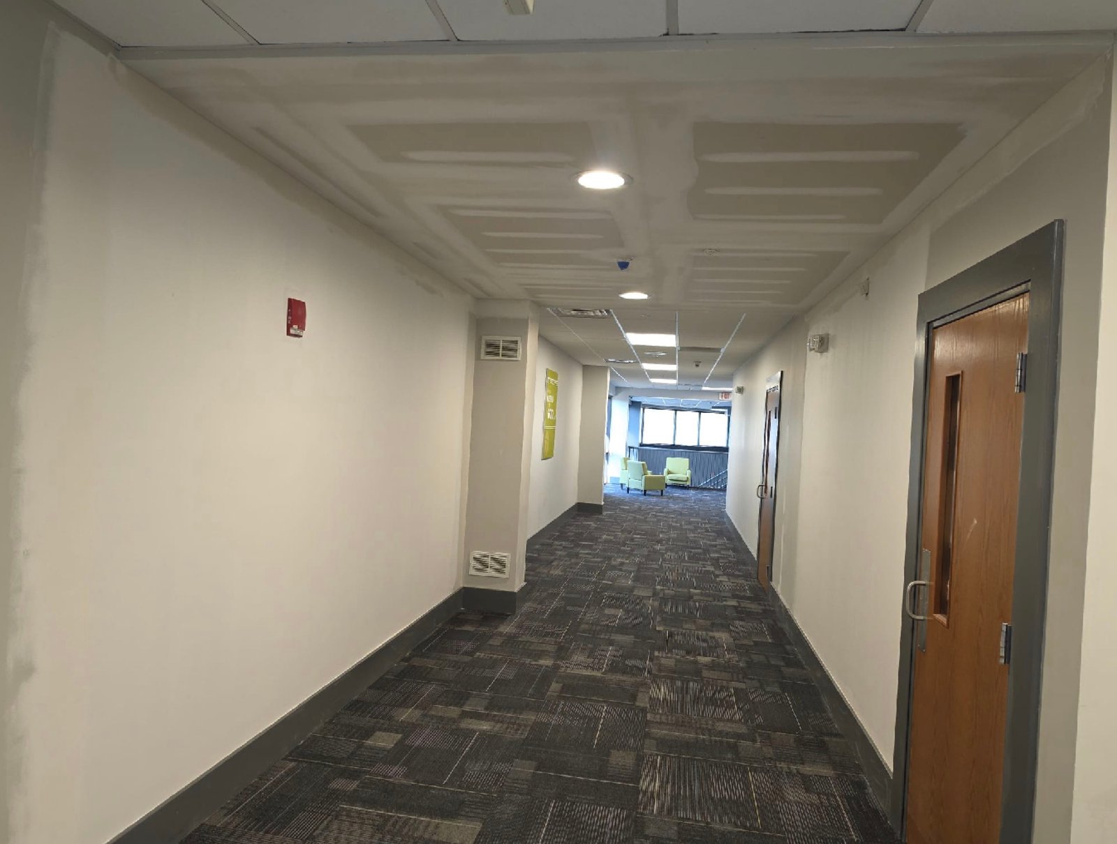 Renovated commercial corridor with finished ceiling, painted walls and new carpet tile
