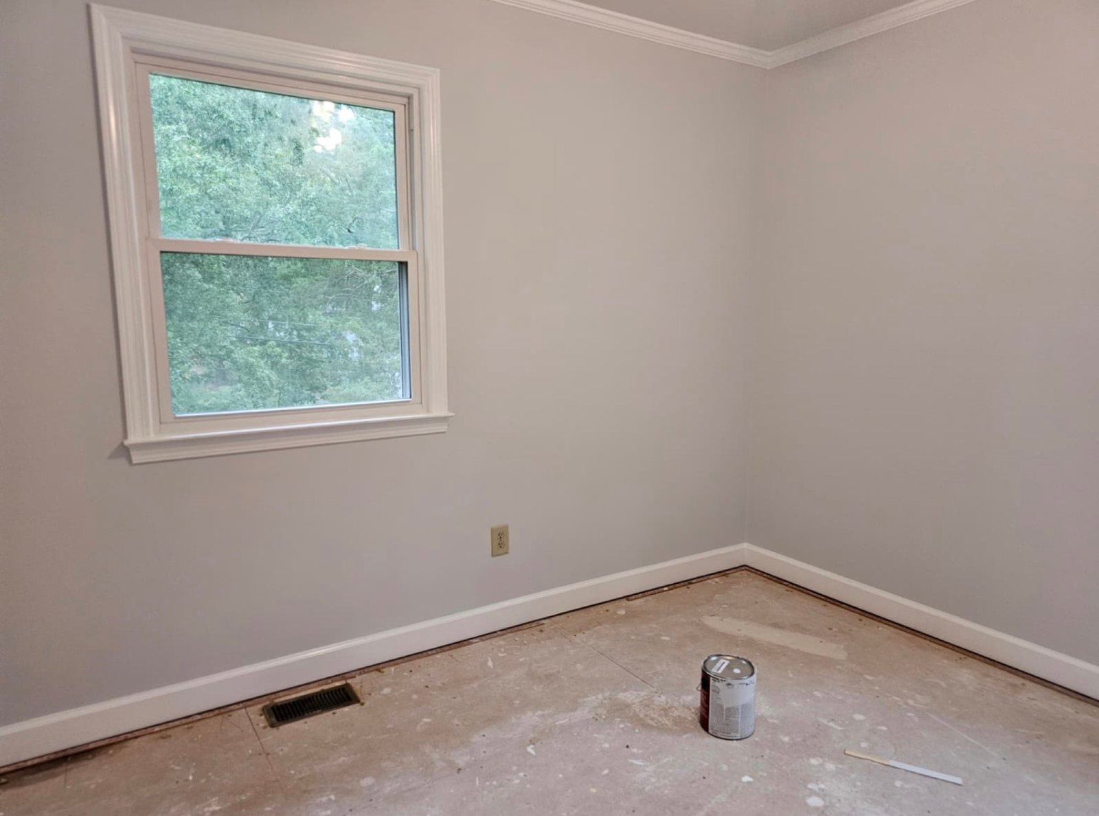 Finished residential bedroom with smooth grey walls, white crown molding and window trim