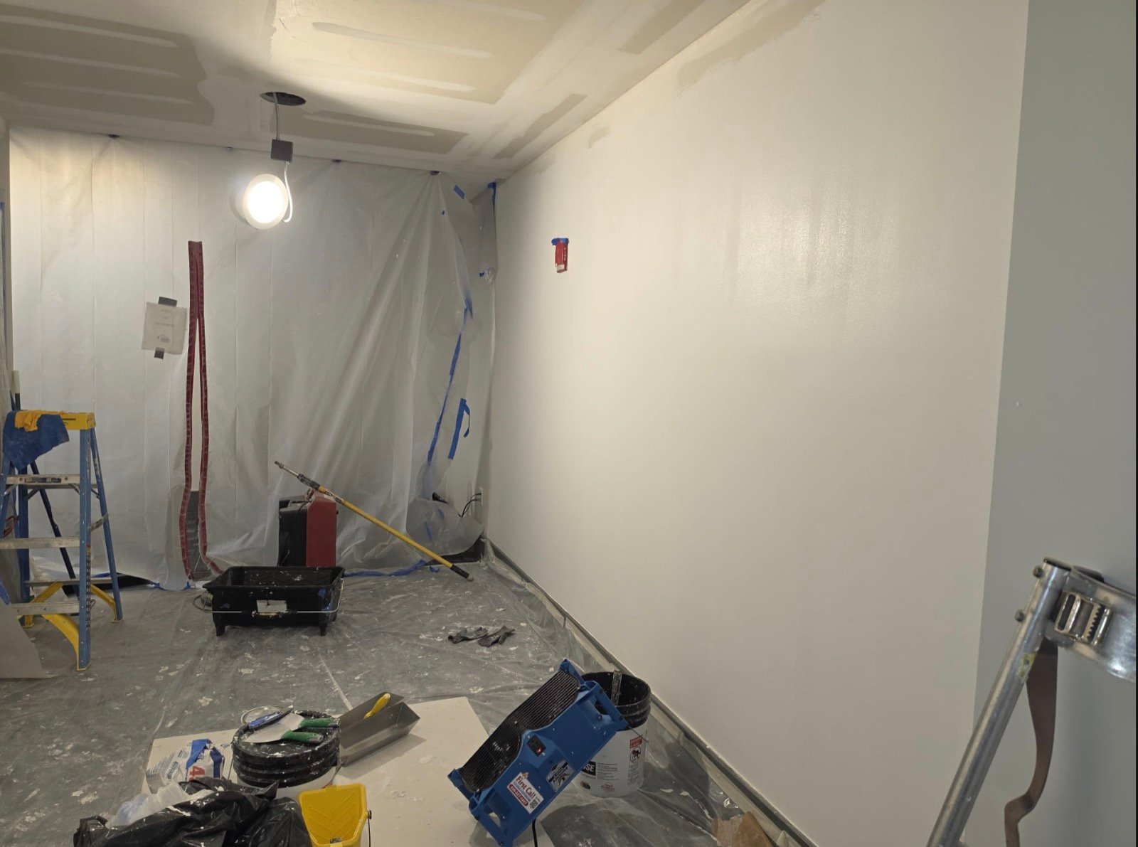 Freshly painted commercial wall with containment plastic and floor protection in place